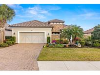 Charming single-story home featuring a tile roof, brick driveway, two-car garage, and lush landscaping at 5011 Tivoli Run, Bradenton, FL 34211