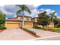 Charming home featuring a tile roof, brick driveway and lush landscaping at 7106 Grand Estuary Trl # 102, Bradenton, FL 34212