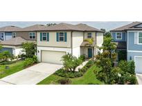 Two-story home boasts a front-facing two-car garage, a light beige exterior, and is complimented with lush landscaping at 9148 Royal River Cir, Parrish, FL 34219