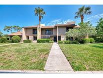 Inviting condo with a lush green lawn and mature palm trees against a bright blue sky at 933 Sunridge Way # B5, Sarasota, FL 34234