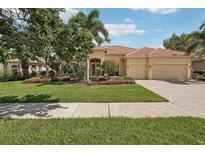 Charming home features a tile roof, a three-car garage, and lush landscaping at 1251 Tuscany Blvd, Venice, FL 34292