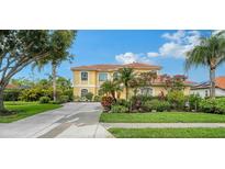 Beautiful yellow two-story home with a tile roof, well-maintained landscaping, and a long driveway at 12520 Natureview Cir, Bradenton, FL 34212
