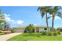 Charming single-story home featuring a lush green lawn, tropical landscaping, and an attached two-car garage at 1334 De Prie Rd, Englewood, FL 34223