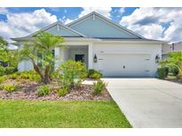 Charming single-story home features a two-car garage and meticulously landscaped front yard with palm trees at 13549 Old Creek Ct, Parrish, FL 34219