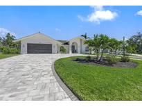 Beautiful single-story home with a well-manicured lawn and inviting, tiled driveway and arched entryway at 1527 Buoy Ln, Osprey, FL 34229