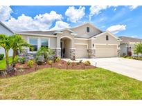 Charming single-story home with a well-manicured lawn, stone accents, and a three-car garage at 17547 Cantarina Cv, Bradenton, FL 34211