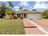 Charming single-story home with a well-maintained lawn, brick driveway, and a two-car garage at 3698 N Chamberlain Blvd, North Port, FL 34286
