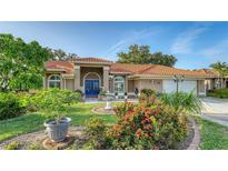 Charming single-story home with a well-manicured lawn, mature trees, and a red tile roof at 387 Eden Dr Dr, Englewood, FL 34223
