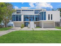 Modern waterfront home with sleek white exterior, glass windows, and an expansive driveway with manicured lawn at 4035 Bay Shore Rd, Sarasota, FL 34234