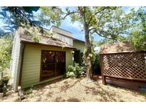 Charming exterior of a home with wood siding, mature trees, and a decorative lattice accent at 4042 S Lockwood Ridge Rd, Sarasota, FL 34231