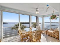 Bright sunroom with tile floors and large sliding glass doors overlooking a beautiful bay, complete with table and seating at 4310 Falmouth Dr # 307, Longboat Key, FL 34228