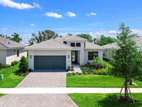 Beautiful single-story home featuring a gray roof, lush landscaping, and a two-car garage at 4988 Fairhope Cir, Lakewood Ranch, FL 34211