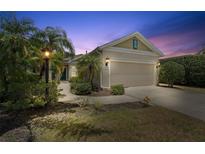 Charming home featuring a two-car garage, neat landscaping, and inviting outdoor lighting at 5047 Newport News Cir, Bradenton, FL 34211