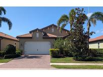 Charming single-story home with a brick driveway, two-car garage, and lush landscaping at 119 Maraviya Blvd, Nokomis, FL 34275