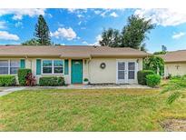Charming single-story home featuring a vibrant green door, lush landscaping, and a welcoming front yard at 1906 Canterbury Ln # 16, Sun City Center, FL 33573