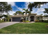 Charming single-story home featuring lush landscaping, a two-car garage, and a welcoming front entrance at 2149 Muskogee Trl, Nokomis, FL 34275