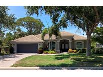 Charming single-story home with a tile roof, double front door, lush landscaping, and a two-car garage at 2149 Muskogee Trl, Nokomis, FL 34275