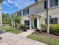 Charming townhouse featuring a well-kept lawn, lush landscaping, and a vibrant green front door at 262 Cape Harbour Loop # 101, Bradenton, FL 34212