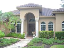 Inviting home exterior with arched entry, decorative columns, and meticulously maintained landscaping at 3230 Charles Macdonald Dr, Sarasota, FL 34240