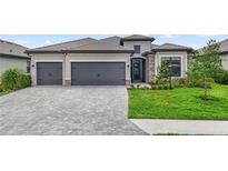 Charming home boasts a three-car garage, stone accents, tile roof, lush landscaping, and a brick paver driveway at 4971 Oyster Pearl St, Bradenton, FL 34211