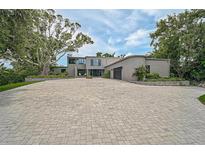 Expansive brick driveway leads to a contemporary stucco home with mature landscaping at 512 Treasure Boat Way, Sarasota, FL 34242