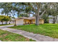 Charming single-story home with a well-manicured lawn and mature trees, showcasing curb appeal at 5823 Helen Way, Sarasota, FL 34243