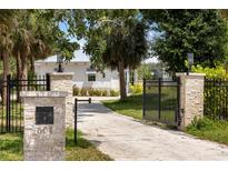 Charming home featuring a stone gate entrance with a long private driveway and lush landscaping at 601 Suffolk Cir, Nokomis, FL 34275