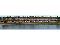 Three story exterior view of the building with lush landscaping and ample parking at 6400 46Th N Ave # 113, Kenneth City, FL 33709