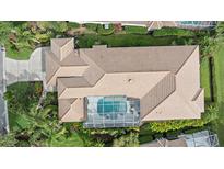 Aerial view of a home with a screened-in pool and well-manicured landscaping, surrounded by lush greenery at 7507 Ascot Ct, University Park, FL 34201