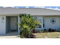 Charming single-story home featuring a well-manicured lawn, tropical plants, and a light gray exterior paint at 217 Mariner Ln, Rotonda West, FL 33947
