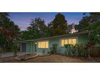 Charming single-story home features fresh mint paint and complemented by lush landscaping at twilight at 2212 Vinson Ave, Sarasota, FL 34232