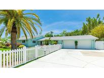 Charming light-blue home with a white picket fence, palm tree, and a driveway leading to a two-car garage at 5238 Susan Ave, Sarasota, FL 34231