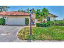 Front exterior of the home boasts a red tile roof, attached garage, and lush landscaping for enhanced curb appeal at 5651 Golf Pointe Dr # 5651, Sarasota, FL 34243