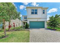 Charming two-story home with a lush landscaped yard and a teal garage door that adds a touch of color at 5735 Bungalow Grove Ct, Palmetto, FL 34221