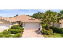 Charming home featuring a tile roof, brick driveway, and well-maintained landscaping with vibrant greenery and a mature palm tree at 5866 Guarino Dr, Sarasota, FL 34238