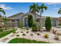 Charming single-story home with lush tropical landscaping, stone pathway, and a vibrant turquoise front door at 6113 55Th E Ter, Bradenton, FL 34203