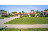 Well-manicured lawn and landscaping accent this beautiful single-story home with a red-tile roof at 7804 Broadmoor Pines Blvd, Sarasota, FL 34243