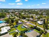 Aerial view of a lovely home with a backyard pool, green lawn and lush surrounding landscaping at 1723 Laramie St, Sarasota, FL 34231