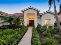 Inviting front entrance featuring double doors, lush landscaping, and a red tile roof, providing curb appeal at 4492 Del Sol Blvd, Sarasota, FL 34243