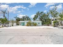 Charming single-story beach home featuring a metal roof and tropical landscaping and a large, sandy yard at 5026 Calle Minorga, Sarasota, FL 34242