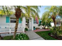 Charming single-story home with white picket fence, turquoise shutters, and lush tropical landscaping at 594 Spanish S Dr, Longboat Key, FL 34228