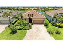 Charming home with tile roof, brick driveway, and lush landscaping near a tranquil lake at 6756 Chester Trl, Lakewood Ranch, FL 34202