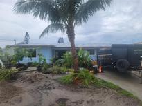 Light blue ranch home with a large palm tree in the front yard and a trailer parked in the driveway at 754 Gran Kaymen Way, Apollo Beach, FL 33572