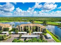 Stunning aerial view of condo complex overlooking a serene lake and lush golf course under a partly cloudy sky at 7911 Grand Estuary Trl # 102, Bradenton, FL 34212