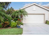 Charming home with a lush, landscaped front yard and a two-car garage with light stucco at 8224 Simpson Falls Ct # 8224, Sarasota, FL 34243