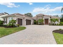 Stunning home exterior boasts a three-car garage, tile roof, and a brick-paved driveway at 1015 143Rd Ne St, Bradenton, FL 34212
