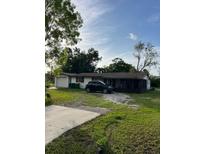 Cozy single-story home features a large front yard and a car parked in the driveway at 14396 Pambar Ave, Port Charlotte, FL 33953