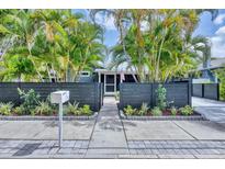 Charming home with a dark grey privacy fence surrounded by lush landscaping and beautiful palm trees at 1919 Laurel St, Sarasota, FL 34236