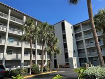 Low angle shot of the condo building with balconies and palm trees under a bright blue sky at 3272 Lake Bayshore Dr # 515, Bradenton, FL 34205