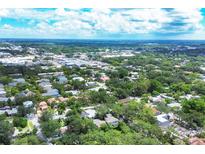 Expansive aerial view showcasing the neighborhood's lush greenery, blue skies, and vibrant cityscape at 3837 Camino Real, Sarasota, FL 34239